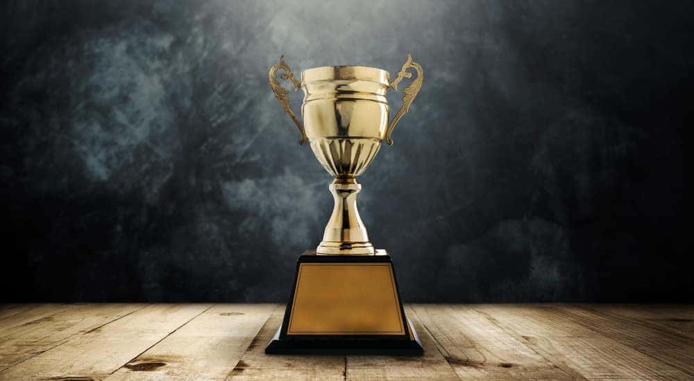 Gold trophy sitting on a brown wooden table in front of a black wall