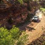 White 2017 Chevrolet Colorado pickup truck driving down a dirt path next to a cliff