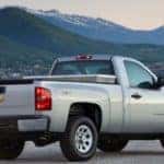 Silver 2013 Chevrolet Silverado 1500 pickup truck parked on pavement in front of tall mountains