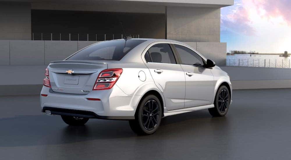 Silver 2018 Chevrolet Sonic parked on cement next to a cement building
