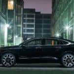 Black 2016 Chevrolet Impala parked in an alley between tall city buildings