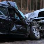 Front of a black vehicle smashed into the front of a silver vehicle on the road