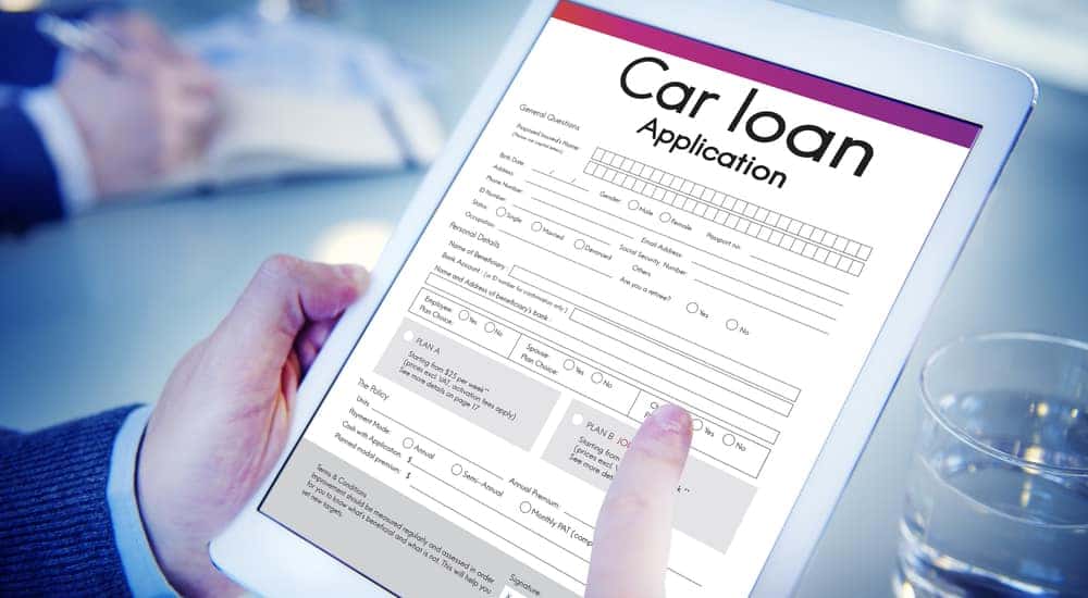 Hands holding a tablet with a car loan application on the screen