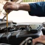 Car mechanic performing work under the hood of a vehicle