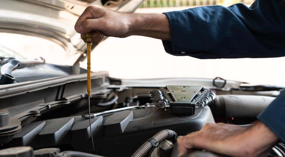 Car mechanic performing work under the hood of a vehicle