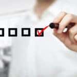 Man in a white button up checking off floating black boxes with a red marker