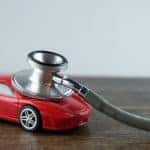 Red toy car sitting on a brown table with a stethoscope on top of it