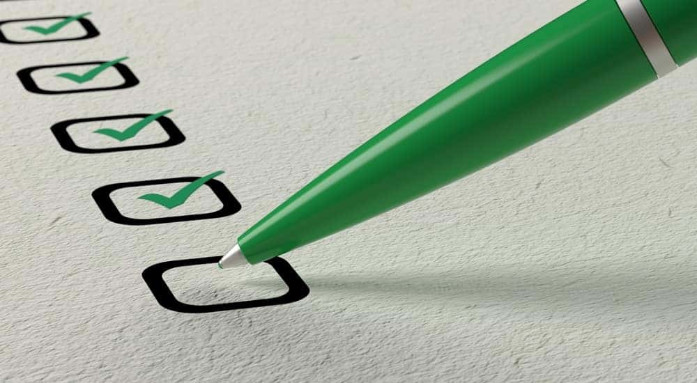 Black boxes on a white piece of paper with green check marks in them being drawn by a pen