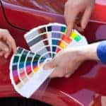 Body shop technician holding paint swabs next to a vehicle to show a customer