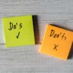 Green sticky note with the word "Do's" written on it with a checkmark next to an orange sticky note with the word "Don'ts" on it with an x mark, sitting on a grey surface
