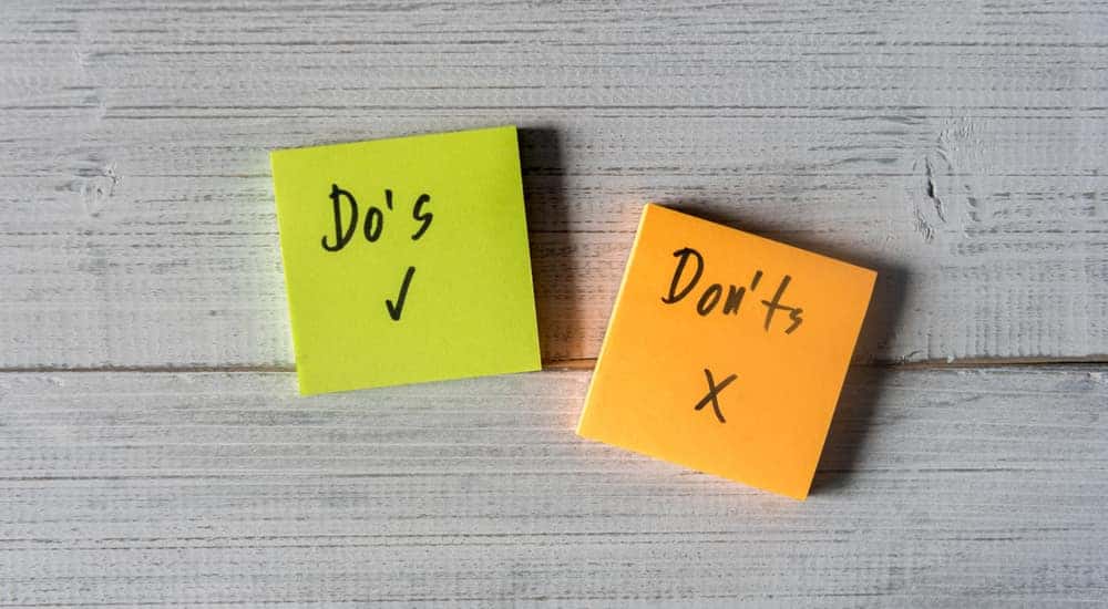 Green sticky note with the word "Do's" written on it with a checkmark next to an orange sticky note with the word "Don'ts" on it with an x mark, sitting on a grey surface