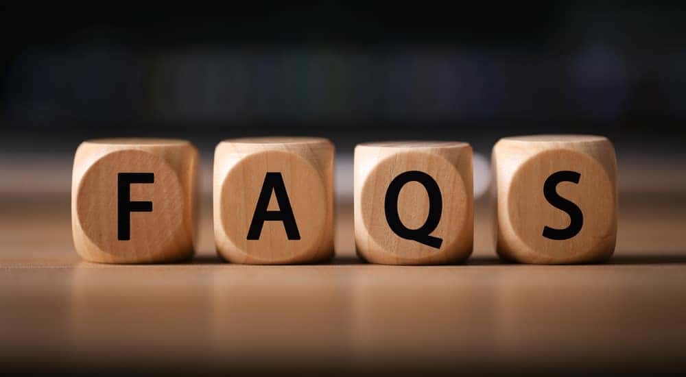 Brown wooden die with letters on them that spell out "FAQS" sitting on a brown table