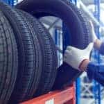 Man grabbing a tire off an orange shelf of tires