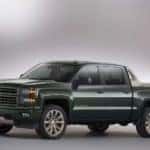Green 2014 Chevrolet Silverado 1500 pickup truck parked in an all-white showroom with backlighting