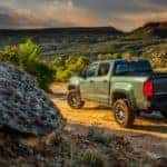 Green 2017 Chevrolet Colorado pickup truck parked at the edge of a dirt trail high up in the mountains
