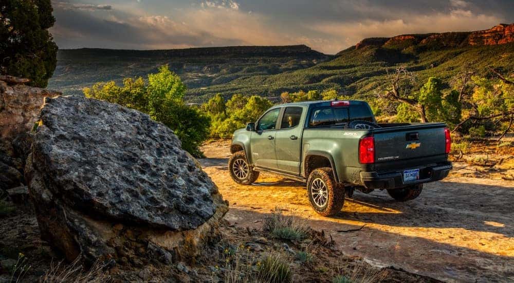 Green 2017 Chevrolet Colorado pickup truck parked at the edge of a dirt trail high up in the mountains