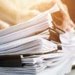 Hands on a stack of papers sitting on a desk