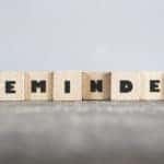 Light brown letter blocks that spell out "REMINDER" sitting on a tan surface