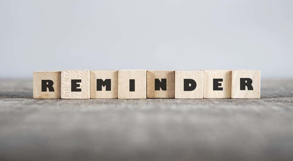 Light brown letter blocks that spell out "REMINDER" sitting on a tan surface