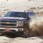 Maroon 2014 Chevrolet Silverado 1500 truck driving through the sand