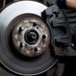 Mechanic wearing black gloves working on a vehicle's brakes