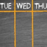 Chalkboard with five parts sectioned off with orange lines and labeled Monday - Friday in white letters