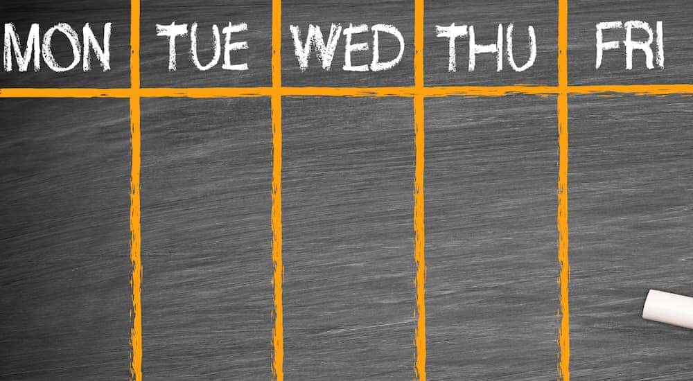 Chalkboard with five parts sectioned off with orange lines and labeled Monday - Friday in white letters