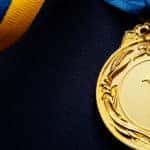 Gold medal with a number one on it attached to a blue and yellow ribbon