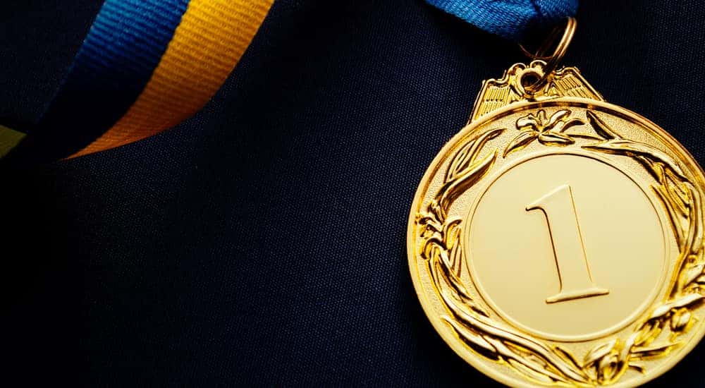 Gold medal with a number one on it attached to a blue and yellow ribbon