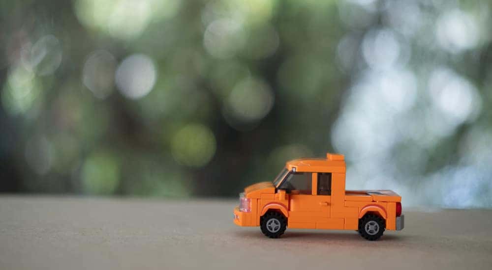 Orange toy truck on a table in front of a blurry green background