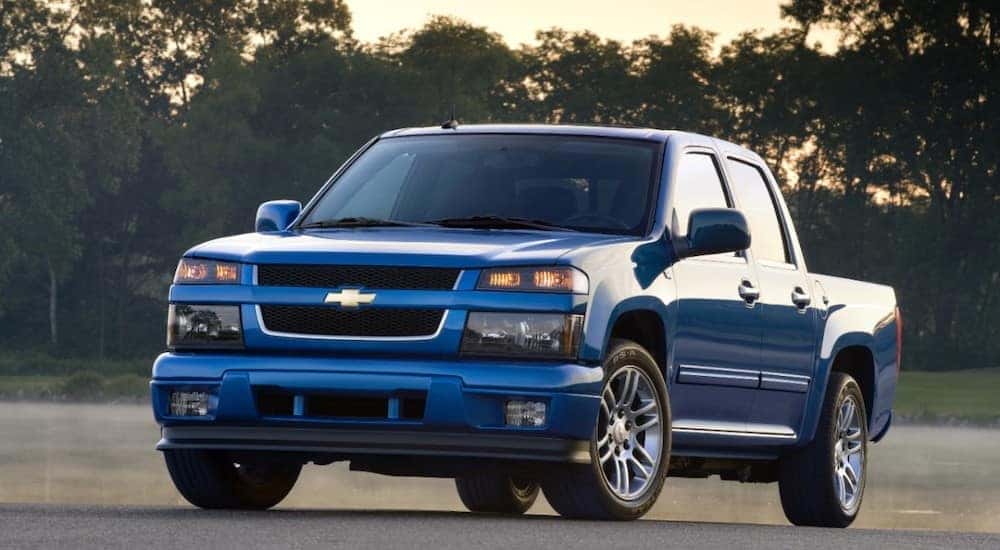 Blue 2011 Chevrolet Colorado parked on pavement in front of water and trees