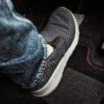 Man's foot in a slip-on sneaker pressing on the brakes of a vehicle