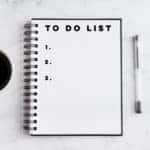 Open notebook next to a cup of coffee and a pen on a white and grey marble table