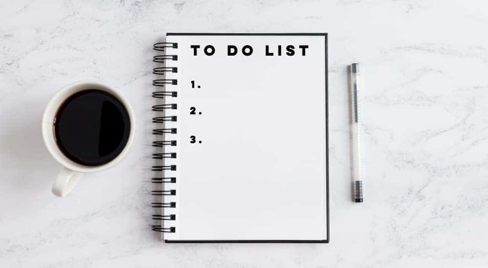 Open notebook next to a cup of coffee and a pen on a white and grey marble table