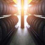 Shelves of tires in front of a yellow post with sunlight peeking through
