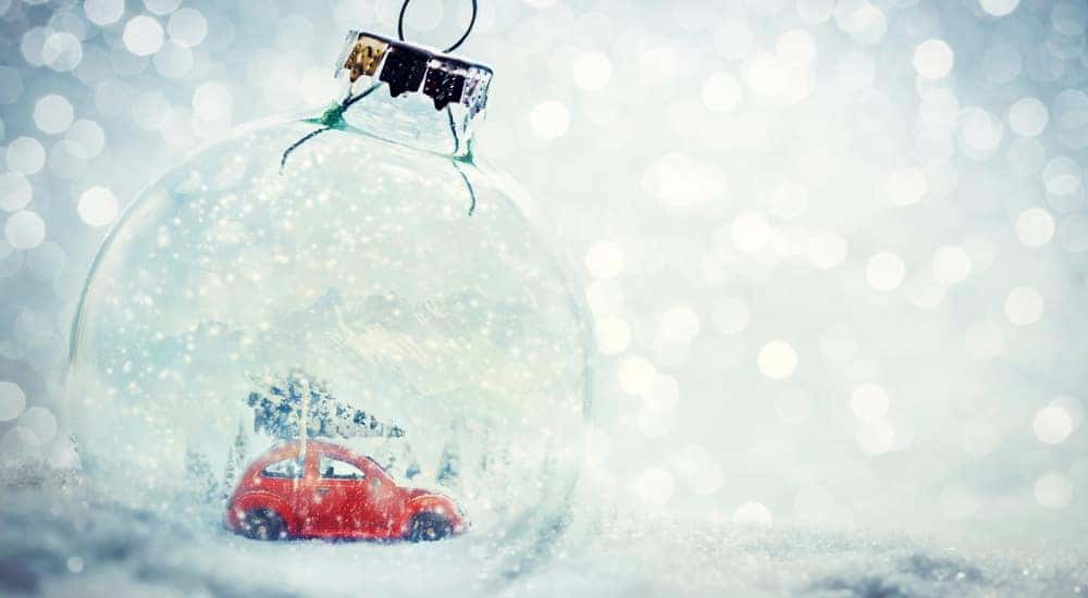 Red toy car inside a clear glass ornament sitting in snow