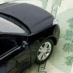 Black toy car on top of one-hundred dollar bills
