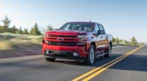 A red 2019 Chevy Silverado 1500 diesel is driving on an empty highway after leaving a used Chevy diesel truck dealer.