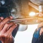 A mechanic is loosening the oil drain plug for an oil change at a used Chevy diesel truck dealer.