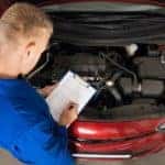A mechanic is shown from a high angle inspecting an engine at an Albany car dealership.