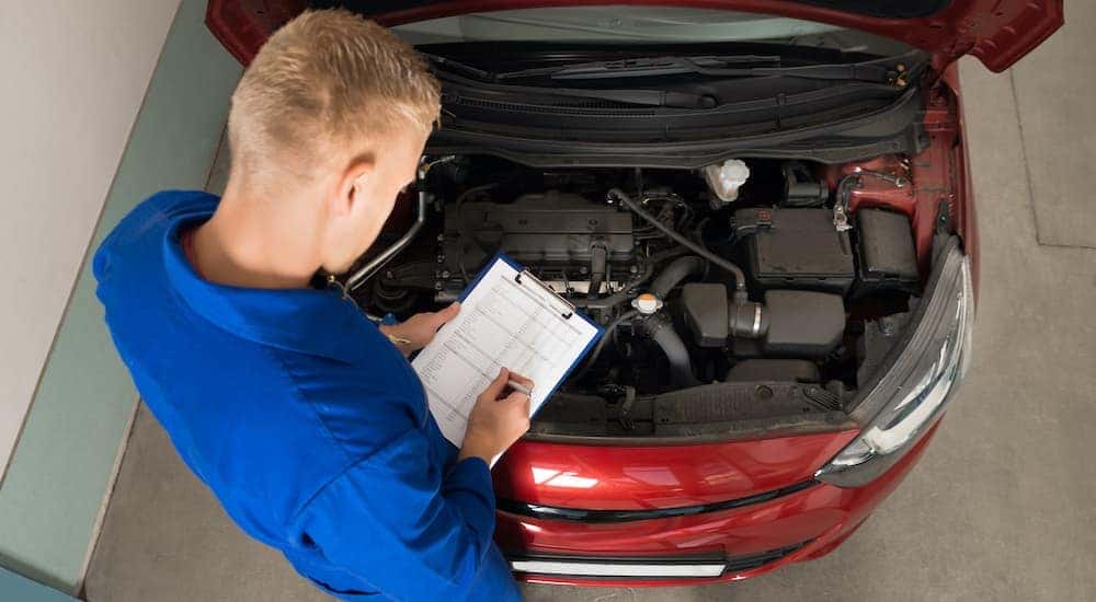 A mechanic is shown from a high angle inspecting an engine at an Albany car dealership.