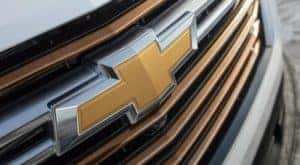 A closeup shows the gold bowtie badging on the grille of a 2022 Chevy Traverse at an Albany Chevy dealership.
