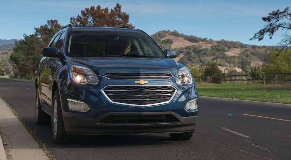 A blue 2017 Chevy Equinox is shown from the front driving on a highway.