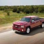 A red 2017 Chevy Silverado is driving on a highway after leaving an Albany used car dealership.