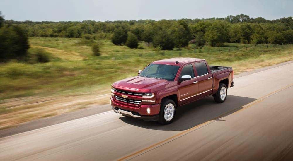 A red 2017 Chevy Silverado is driving on a highway after leaving an Albany used car dealership.