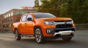 An orange 2021 Chevy Colorado is driving on a city street after leaving a Chevy truck dealer in Albany, NY.
