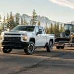 White 2021 Chevy Silverado 2500HD towing construction equipment to a Chevy truck dealer in Albany.