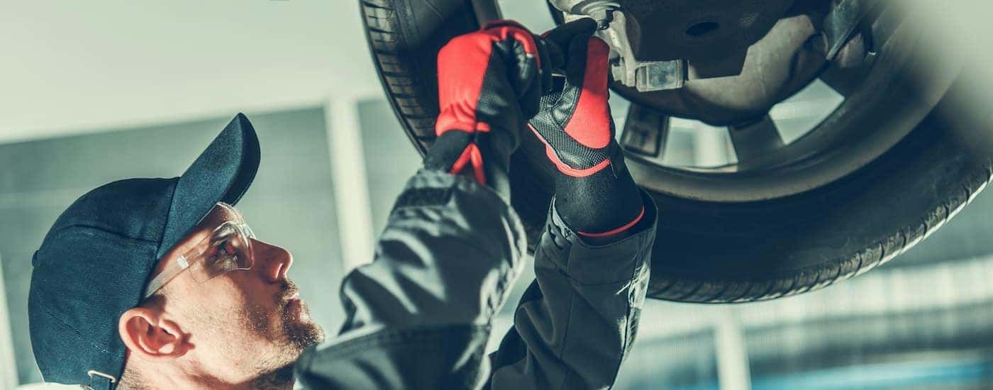 A mechanic is shown servicing a vehicle on a lift at a Chevy car dealership.