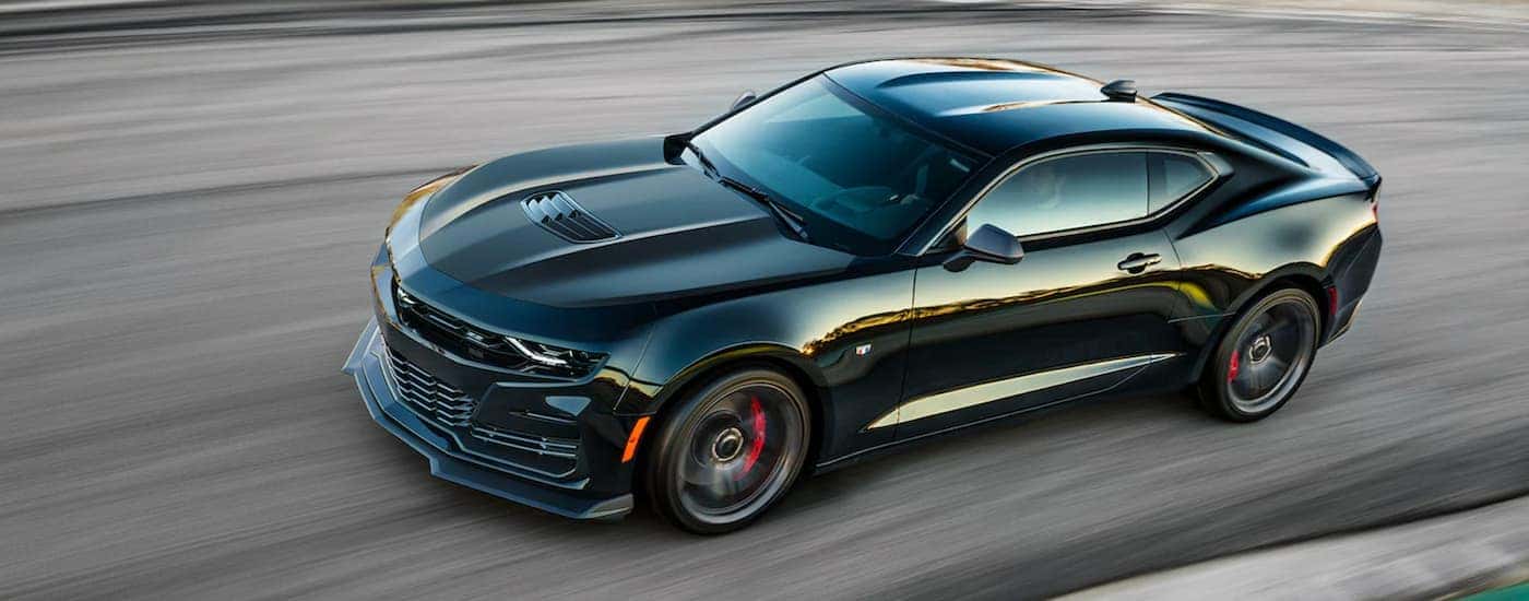 A black 2022 Chevy Camaro is shown from the side driving on a racetrack.