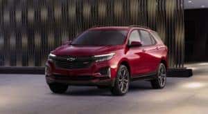 A red 2022 Chevy Equinox is parked in front of a textured wall outside a Schenectady Chevy dealer.